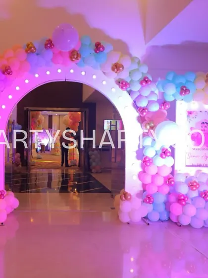 A grand entrance arch for a butterfly party, illuminated with lights and covered in pastel balloons, setting a magical tone for the celebration.