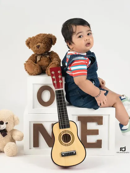 A little musician in the making. Using props like a guitar and "ONE" blocks adds a playful element to the first birthday photoshoot.