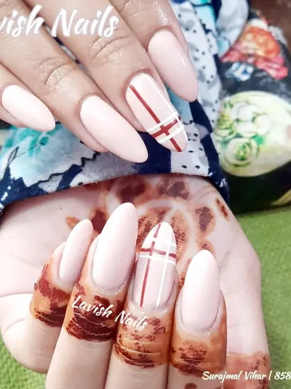 A chic and modern design featuring a neutral base with clean red and white line art on an accent nail, perfectly complementing the geometric patterns of the mehendi.