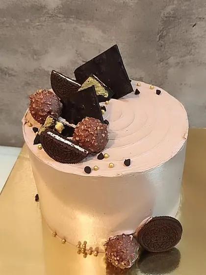 A tall chocolate cake topped with Ferrero Rocher, Oreos, and chocolate shards. A truly decadent treat.