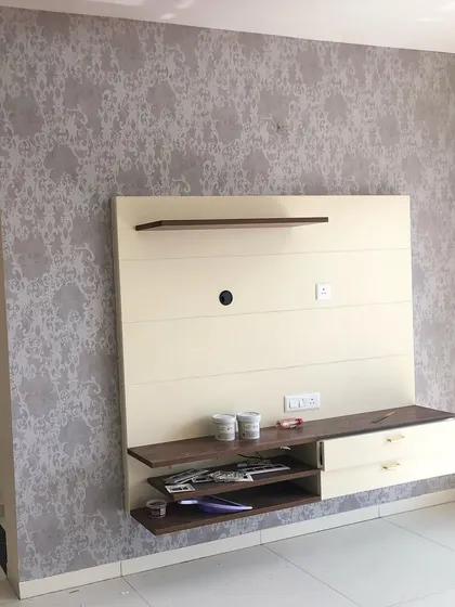 A grey damask-style wallpaper used as a background for a modern TV unit.