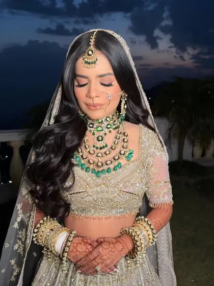 A serene bride at her destination wedding in Mussoorie, her hair styled in classic, open waves under her veil.