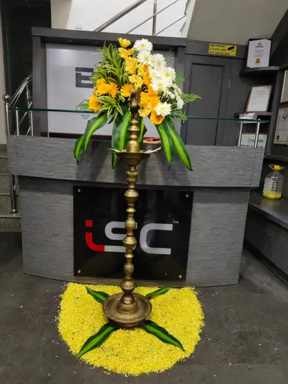 A lamp decoration for the 25th anniversary of Industrial Sales Corporation. The lamp is placed on a bed of yellow flower petals and topped with a fresh bouquet.