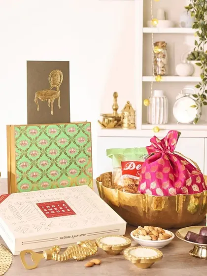 This hamper has a distinctly Indian aesthetic, featuring a hammered brass bowl, a quirky fish-shaped bottle opener, and gift boxes with traditional motifs. It's a perfect blend of modern and ethnic design.