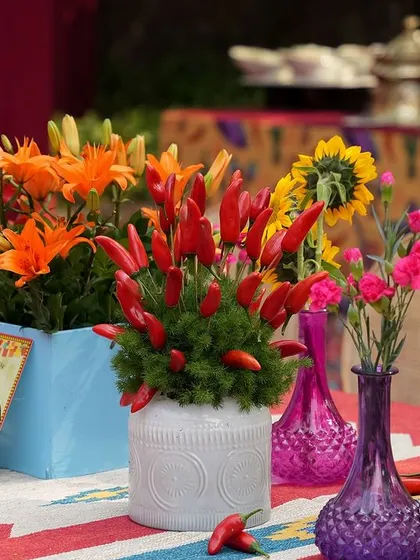 A close-up of the unique centerpieces, which combine flowers like lilies and carnations with bunches of red chillies.