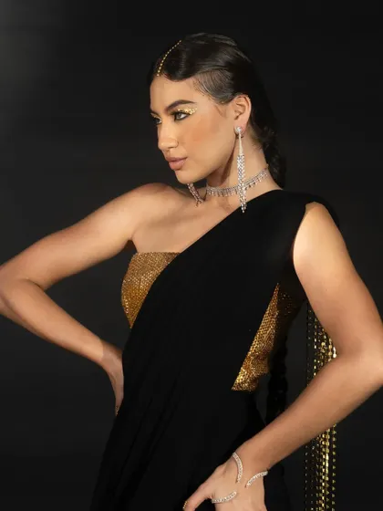 A close-up from the Nikhil Thampi lookbook featuring a black and gold ensemble. The lighting emphasizes the contrast between the two colors and the intricate details of the jewelry.