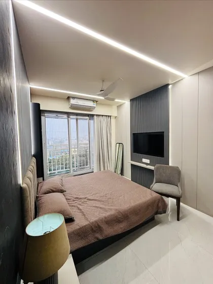 I designed this master bedroom to be a cozy retreat. The combination of dark textured wall panels, soft ambient lighting from the ceiling, and an upholstered headboard creates a warm and inviting modern bedroom.