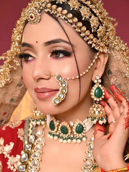 A traditional bridal look with a modern twist. The winged eyeliner is sharp and dramatic, paired with a softer eyeshadow and beautiful green and white kundan jewelry.