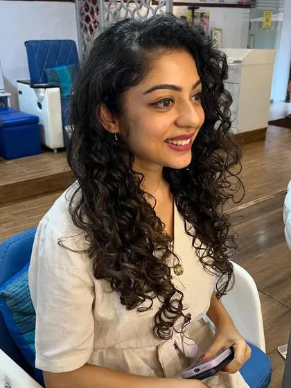 A happy client showing off her healthy, long curly hair.