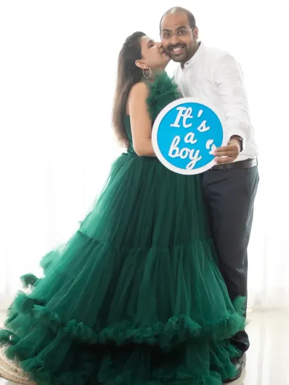 A happy kiss for the dad-to-be as he holds an "It's a boy" sign. A joyful moment captured in our bright and airy studio.