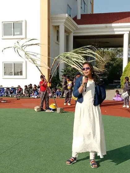 A teacher poses with a sugarcane stalk, embracing the festive spirit of the harvest celebration.