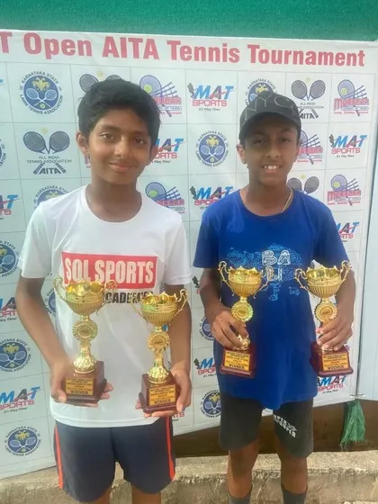Riyaansh Itagi and Tejas Holla showcasing their trophies after a successful State Open Tennis Championship, winning titles in both singles and doubles.
