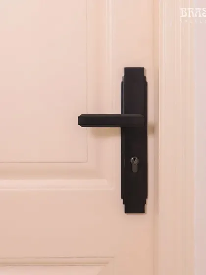 The Natali Lever Handle in a Jet Black finish, installed in a modern Juhu residence. Its design is defined by the clean, stepped detailing of Art Deco, creating a bold, geometric statement against the clean white door.