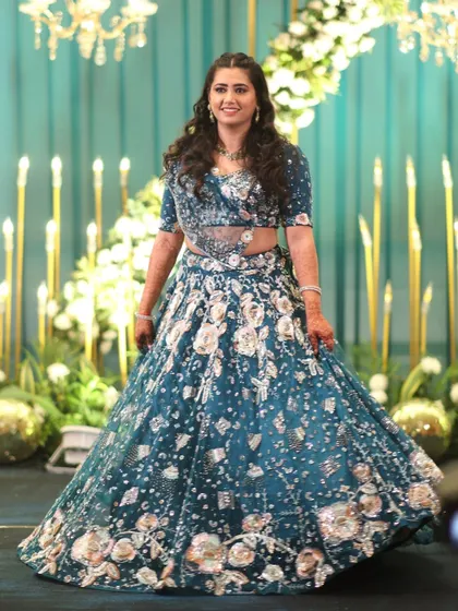 A stunning solo portrait of the bride in her beautiful teal lehenga. The stage lighting and decor are designed to make our clients shine on their special day.