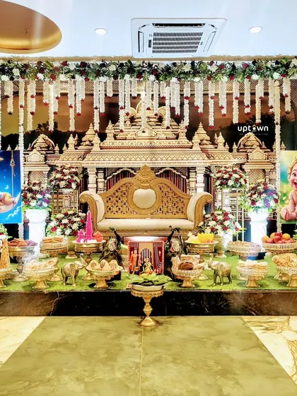 A grand naming ceremony stage with a temple-like structure and Krishna-themed decor.