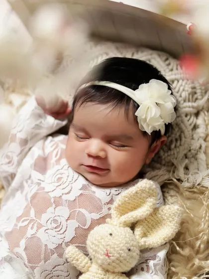 A close-up of a sleeping newborn girl holding a tiny knitted bunny. Props like these add a touch of sweetness to the portraits.