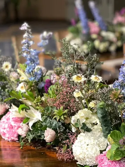 A close-up of a table centerpiece from the Italian garden wedding, featuring a vibrant mix of delphiniums, hydrangeas, and other wildflowers.