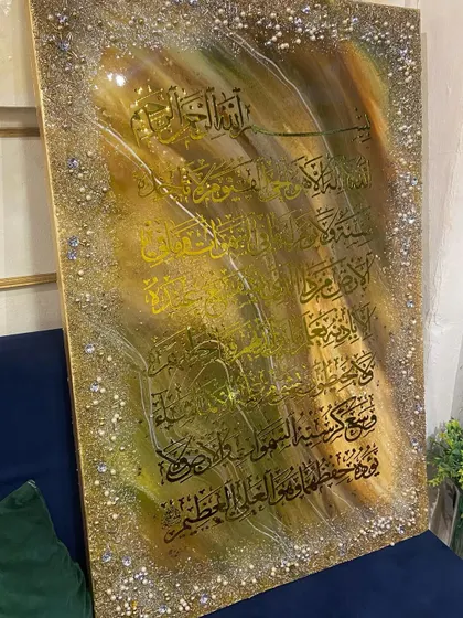 This Ayat al-Kursi artwork features black calligraphy on a shimmering gold and brown background, fully bordered with textured crystals for a rich, opulent look.