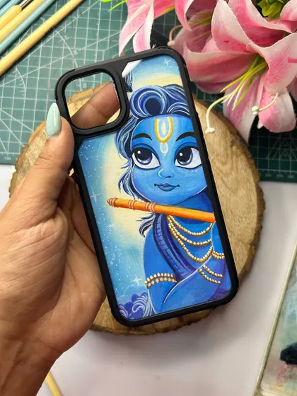 A finished hand-painted phone cover featuring a cute illustration of Krishna playing his flute. This is a perfect way to keep a reminder of divine music and peace with you.
