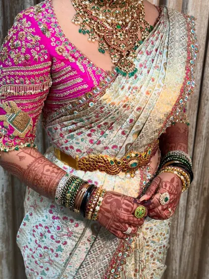 A stunning bridal look where the saree drape is as important as the hair and makeup. The pleats are neat, the pallu is perfectly placed, and the vaddanam completes the look.