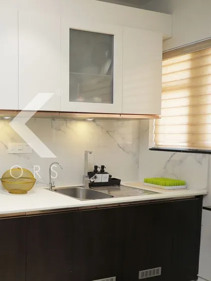 This view highlights the sink area and the combination of closed and glass-front cabinets. The design is practical, with everything within easy reach for a seamless cooking experience.