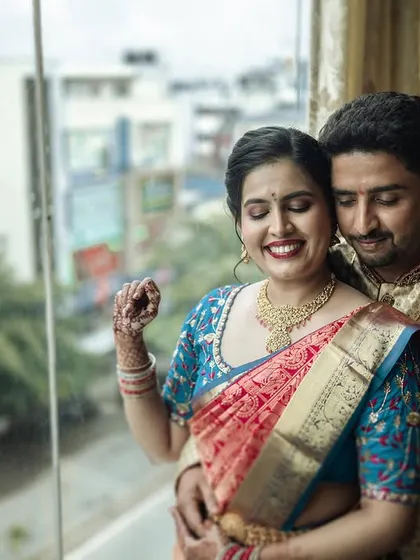 A happy, candid embrace from Padmashree and Nikil's engagement. The natural light from the window creates a beautiful, soft glow.