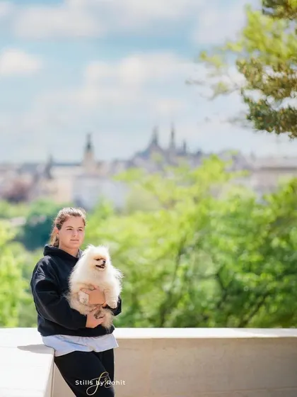 A casual, happy moment with a woman and her Pomeranian, Bueno, enjoying the view in Prague. Sometimes the best shots happen when you're just relaxing and taking in the scenery together.