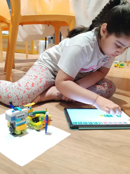 This student is in deep concentration, programming her robot on a tablet to perform a specific task.