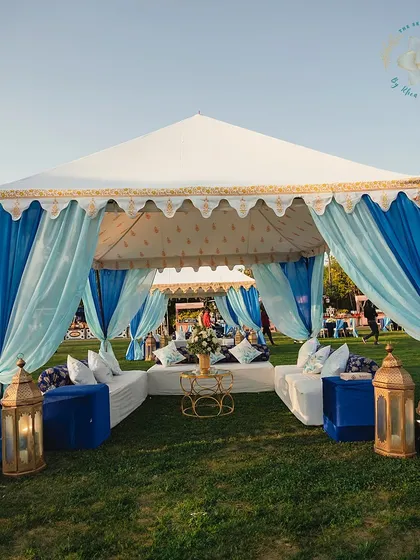 A beautiful tented seating area provides shade and a sense of intimacy for guests at the outdoor Mehendi Sangeet. The flowing blue drapes add a touch of softness and color.