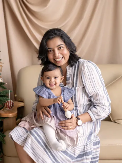 A mother and daughter share a smile during a Christmas-themed shoot. The festive background adds a touch of holiday magic to this sweet moment.
