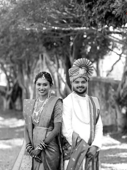 A classic black and white portrait of the bride and groom. Standing side-by-side in their traditional Maharashtrian wedding attire, they create a timeless and elegant image.