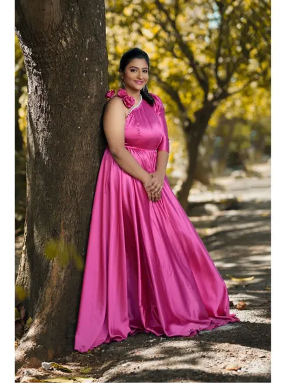 A serene moment captured in a beautiful outdoor setting. The rich pink satin of the gown looks stunning against the natural backdrop of the trees.