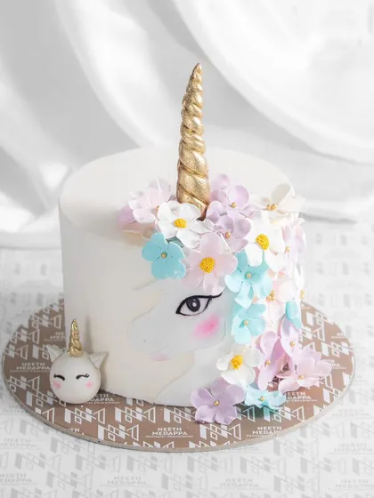 A world of enchantment in one cake. This unicorn-themed creation features a beautiful unicorn face with a golden horn and a mane of pastel flowers.