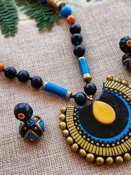 An elegant semi-circular pendant necklace in black, blue, and gold, paired with a cute matching jhumka.