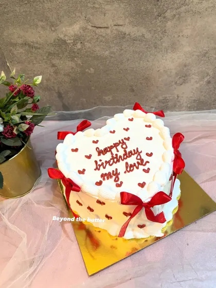 A vintage style heart shaped cake with red ribbons and tiny hearts. It's a romantic and timeless design for a birthday or anniversary.