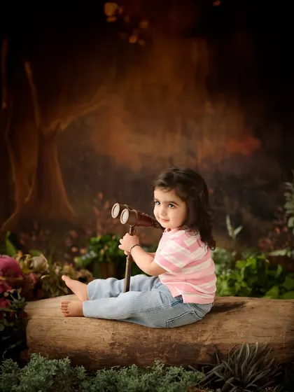 An explorer in an enchanted forest. The dark, moody lighting and rustic props give this sitter session a sense of adventure and mystery.