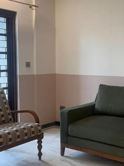 Testing out color combinations on site. The half-painted wall in a dusty rose tone is paired with an olive green sofa.