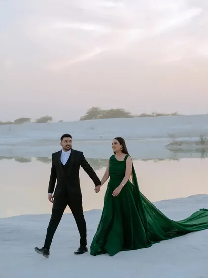 A candid walking shot along the water's edge at sunset. The warm light and the couple's relaxed interaction make this a beautiful and natural pre-wedding photograph.