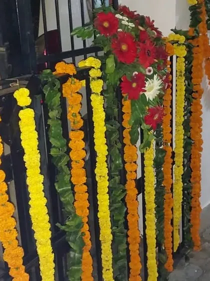 A close-up of the gate and wall decoration for a home wedding. We use a combination of marigold strings and small bouquets of mixed flowers to adorn railings and walls.