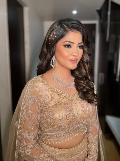 This side view shows how the soft curls and hair accessories complement the elegant makeup for a cohesive sangeet style.