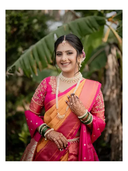 A close-up portrait of the bride, showcasing her beautiful smile, intricate mehndi, and traditional jewelry.