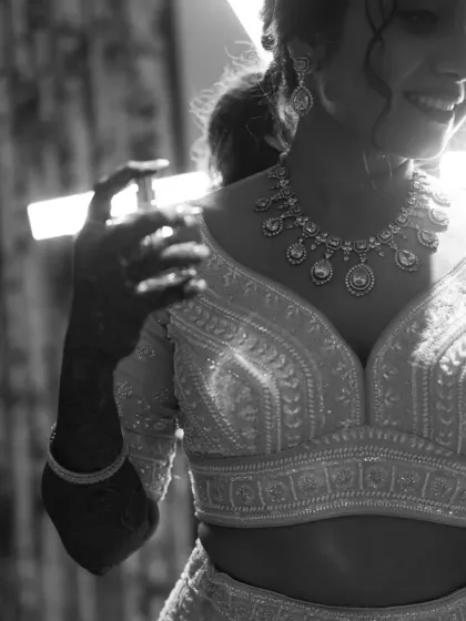 A close-up black and white shot focusing on the intricate jewelry and the bride's happy smile.