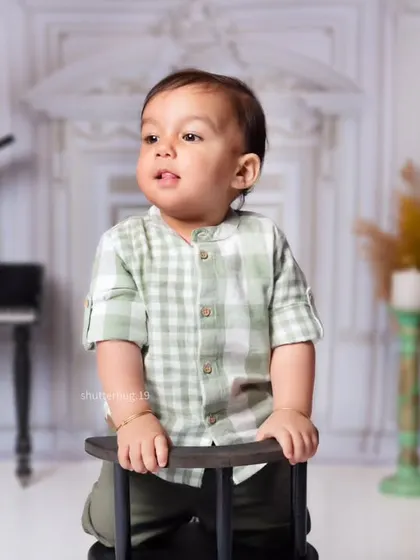 A handsome portrait of a one-year-old boy standing by a chair in our elegant, music-themed studio.