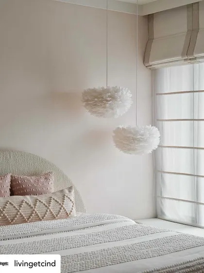 A close-up of the feather pendant lights and textured bedding in the daughter's room, highlighting the soft and tactile nature of the design.