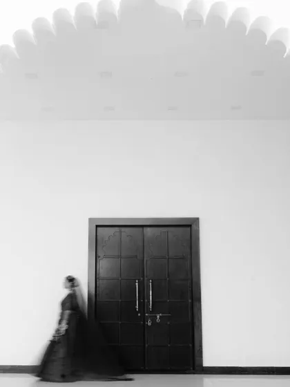 An artistic motion-blur shot of the bride in black and white, creating a sense of movement and mystique against a minimalist background.