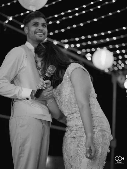 A candid black and white photo of the couple sharing a laugh on stage during their cocktail party.