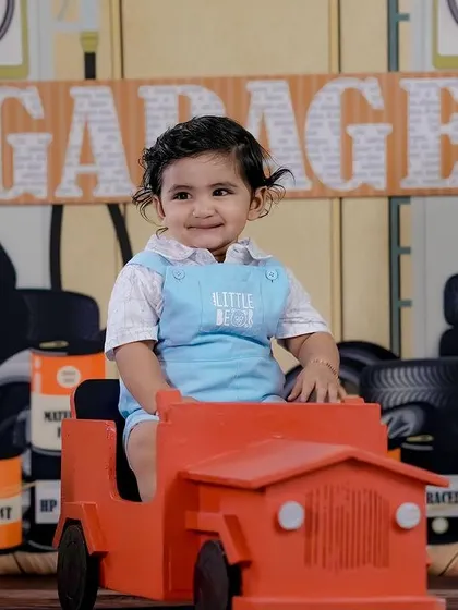 A smiling little mechanic in our garage-themed setup. The details in the background make the scene come to life.