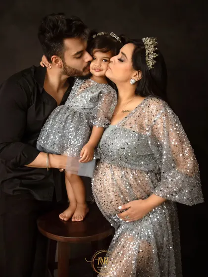 A beautiful family portrait filled with love and affection. Both parents kiss their daughter, creating a heartwarming image during their maternity session.