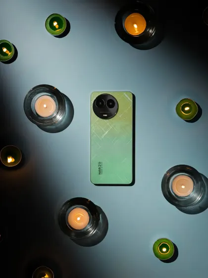 A top down shot of the Narzo phone surrounded by candles, creating a moody and visually interesting pattern of light and shadow.