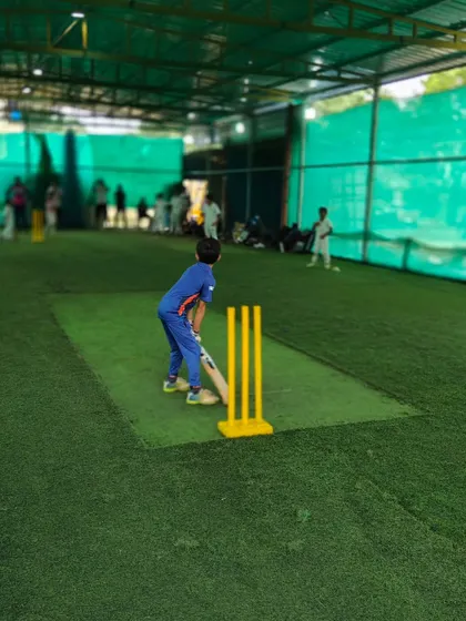 A young player takes his stance, ready to bat during an indoor session. Our all-weather facilities mean that skill development continues, rain or shine.